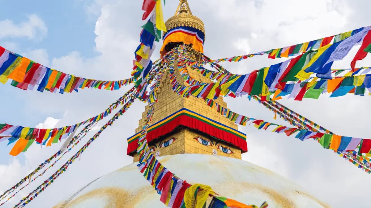 Prayer flags and a golden stupa under a blue sky in Kathmandu